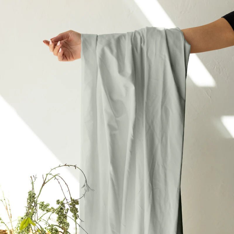 Folded stacks of microfiber, cotton, and Egyptian cotton bed sheets shown side by side