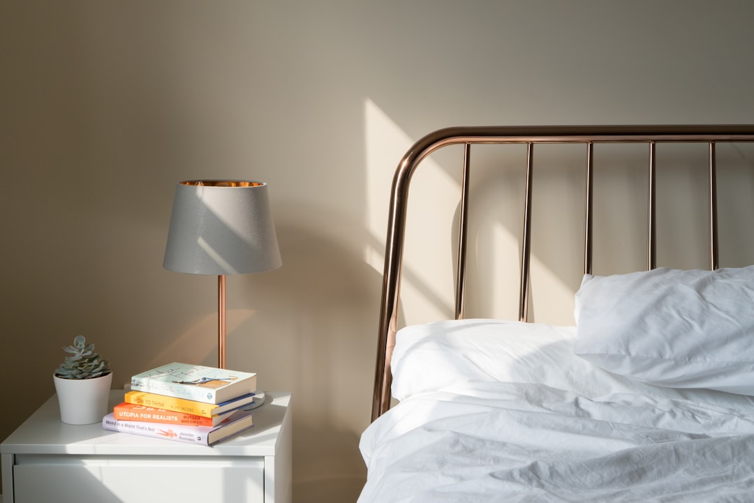 Person sitting on the edge of a freshly made new mattress in a bright bedroom